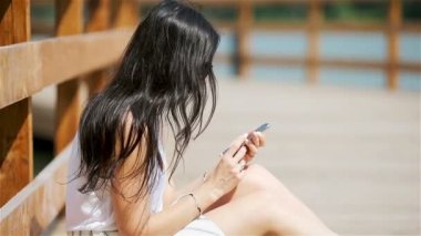 Şirin kadın parkta otururken cep telefonundan mesaj okuyor..