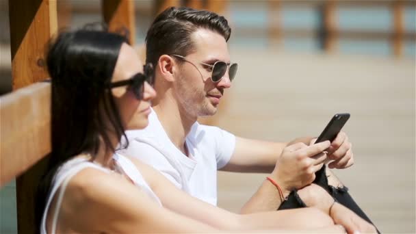 Obrázek radostného páru používajícího smartphony v parku — Stock video