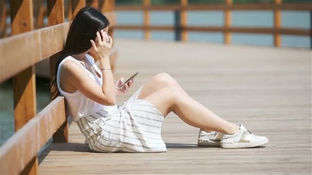 Söt kvinna läser textmeddelande på mobiltelefon när du sitter i parken. — Stockvideo