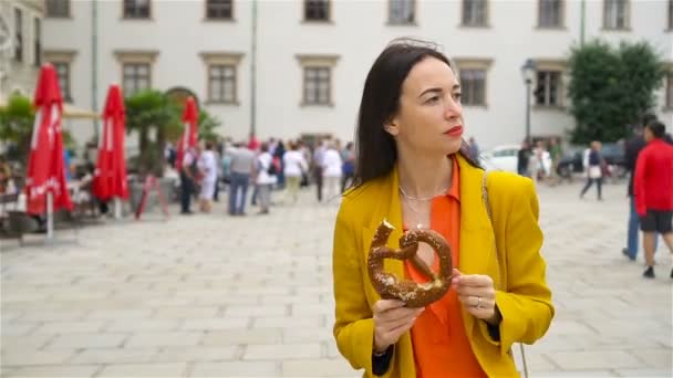 Beautiful young woman holding pretzel and relaxing in park — Stock Video