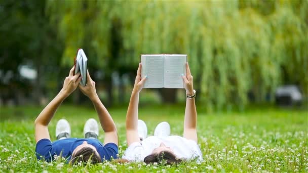 悠闲的年轻夫妇躺在草地上看书 — 图库视频影像