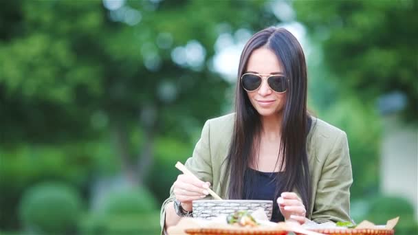 Jovem mulher comendo levar macarrão na rua — Vídeo de Stock