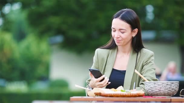 Молода жінка їсть локшину на вулиці — стокове відео