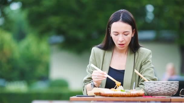 Mujer joven comiendo fideos para llevar en la calle — Vídeos de Stock