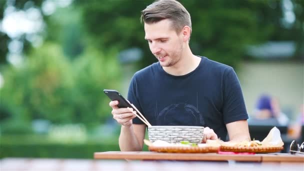 Giovane uomo mangiare portare via tagliatelle per strada — Video Stock