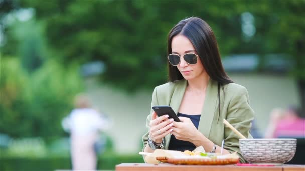 Mujer joven comiendo fideos para llevar en la calle — Vídeos de Stock