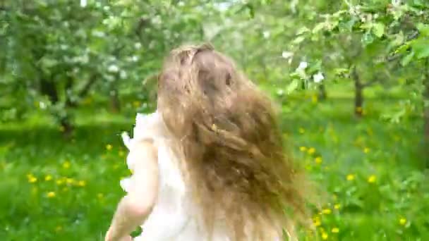 Imádnivaló kislány a virágzó almakertben, gyönyörű tavaszi napon. — Stock videók