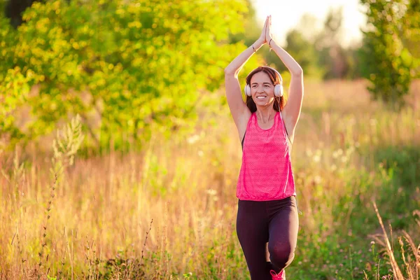 Jovem mulher sorrindo fazendo exercícios esportivos ao ar livre — Fotografia de Stock