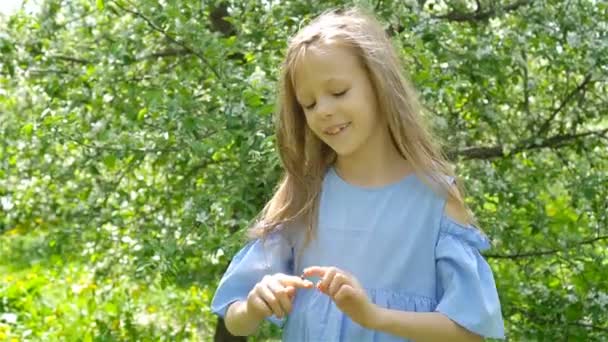 Niña en el jardín de manzanos en flor en el día de primavera juega con la mariquita — Vídeos de Stock