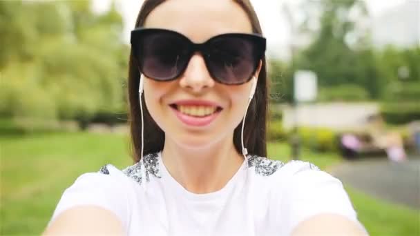 Chica joven haciendo video selfie y divertirse en el parque. Retrato de selfie de estilo de vida de una joven mujer positiva divirtiéndose y tomando selfie . — Vídeos de Stock