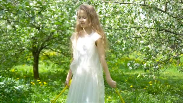 Liebenswertes kleines Mädchen im blühenden Apfelgarten an einem schönen Frühlingstag — Stockvideo
