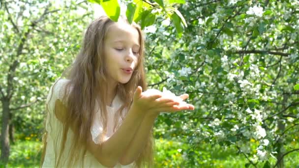 Прекрасная маленькая девочка в цветущем яблоневом саду в прекрасный весенний день — стоковое видео