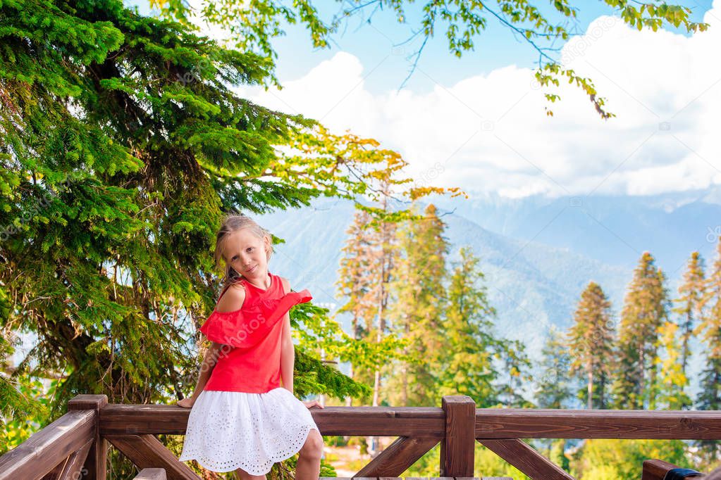 Beautiful happy little girl in mountains in the background of fog