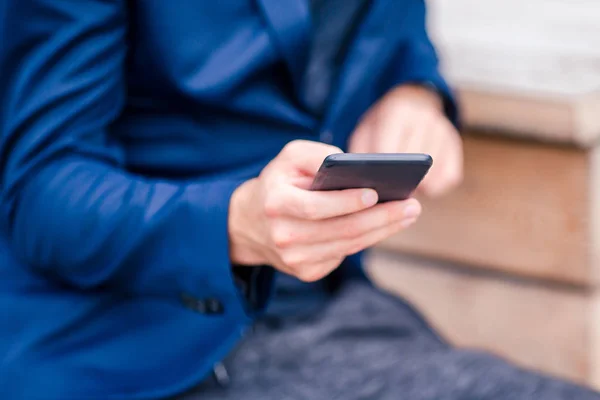 Gros plan des mains masculines tient le téléphone portable à l'extérieur dans la rue. Homme utilisant un smartphone mobile . — Photo