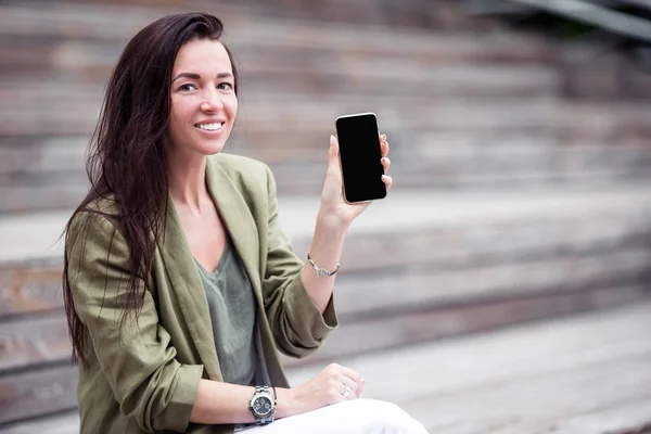 Счастливая женщина со смартфоном на открытом воздухе в городе — стоковое фото