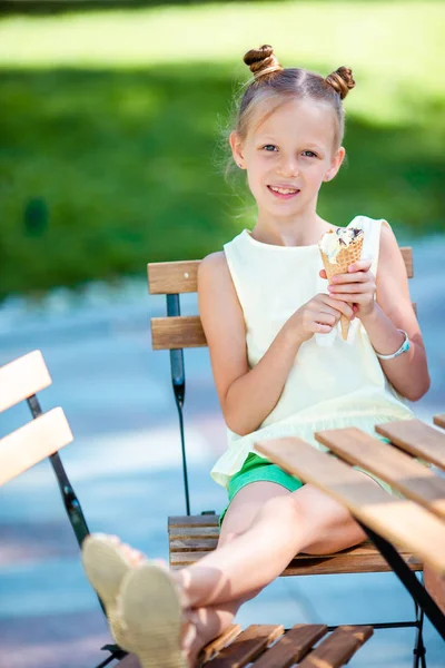 Niña comiendo helado al aire libre en verano en la cafetería al aire libre —  Fotos de Stock