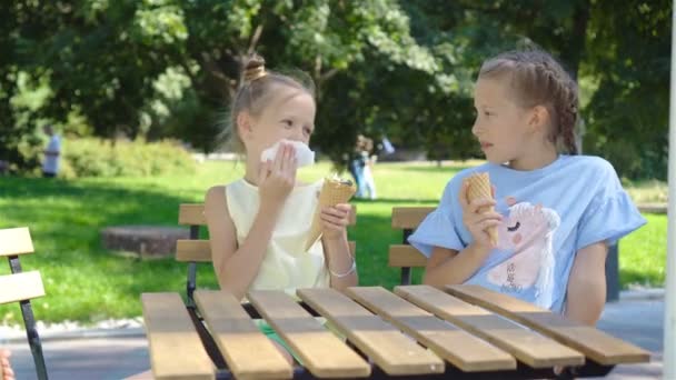 Dziewczynki, jedzenie lodów na zewnątrz w lecie w kawiarni na świeżym powietrzu — Wideo stockowe
