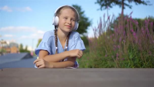 Kleines entzückendes Mädchen hört Musik im Park — Stockvideo