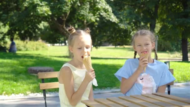 Μικρά κορίτσια τρώνε παγωτό σε εξωτερικούς χώρους το καλοκαίρι στην υπαίθρια καφετέρια — Αρχείο Βίντεο