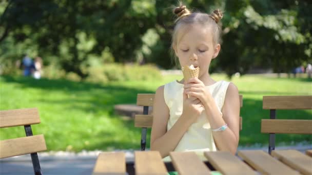 Mała dziewczynka jedzenie lodów na zewnątrz w lecie w kawiarni na świeżym powietrzu — Wideo stockowe