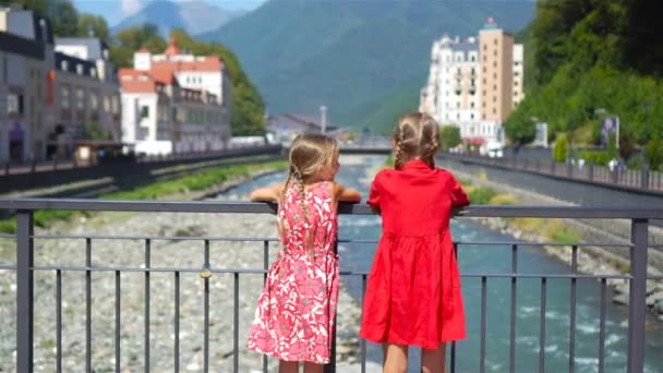 Niñas en el sombrero en el terraplén de un río de montaña en una ciudad europea . — Vídeos de Stock