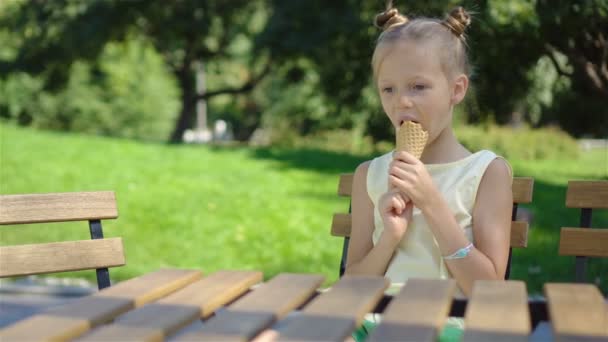 Mała dziewczynka jedzenie lodów na zewnątrz w lecie w kawiarni na świeżym powietrzu — Wideo stockowe