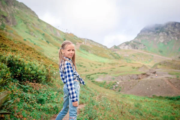 Beautiful happy little girl in mountains in the background of fog — Stock Photo, Image