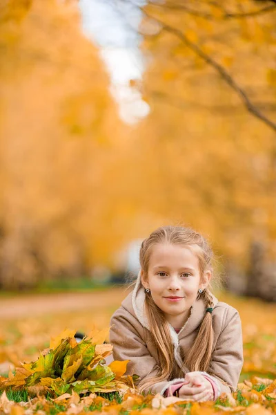 Portrait of adorable little girl outdoors at beautiful warm day with yellow leaf in fall — Stock Photo, Image