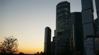 Gökdelen günbatımı güneş gökyüzünde ile üzerinde cam cepheler. Modern şehir iş İlçesi'nde modern binalar.