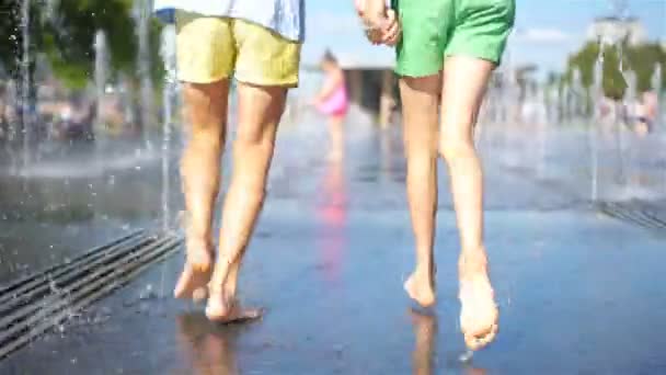 Pequeñas chicas adorables se divierten en la fuente de la calle en el día soleado caliente — Vídeo de stock