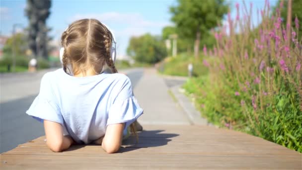 Niña adorable escuchando música en el parque — Vídeo de stock