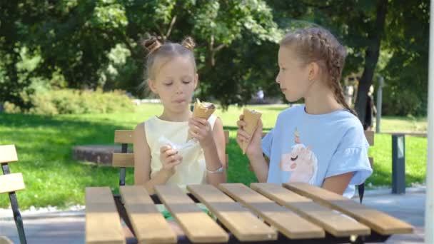 Kleine meisjes eten ijs buiten bij zomer op terras — Stockvideo