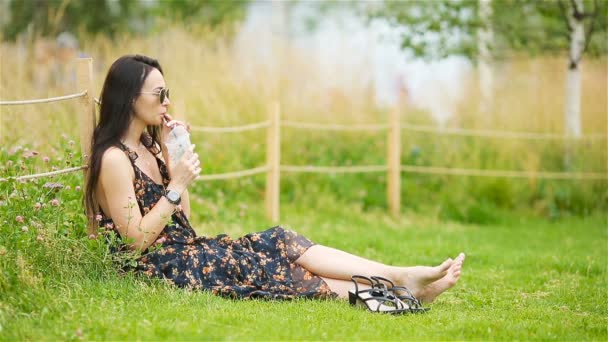 Femme mignonne lit le message texte sur le téléphone portable tout en étant assis dans le parc. — Video