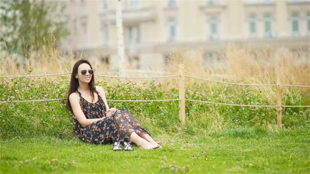 Cute woman is reading text message on mobile phone while sitting in the park. — Stock Video