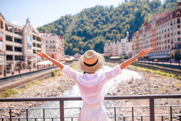 Menina feliz no chapéu no dique de um rio de montanha em uma cidade europeia . — Fotografia de Stock