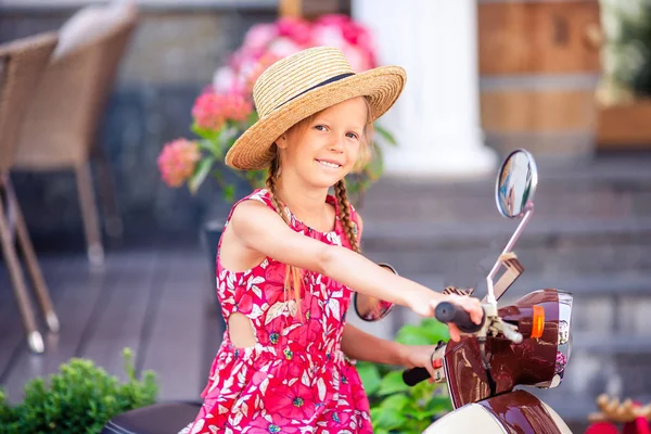 Adorable petite fille en chapeau sur le cyclomoteur à l'extérieur — Photo