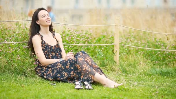 Femme mignonne lit le message texte sur le téléphone portable tout en étant assis dans le parc. — Video