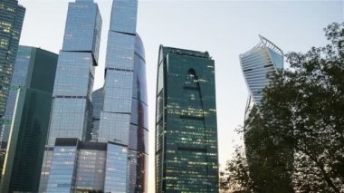 Gökdelen günbatımı güneş gökyüzünde ile üzerinde cam cepheler. Modern şehir iş İlçesi'nde modern binalar.