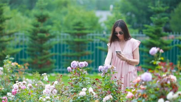 Jovem em um jardim de flores entre belas rosas. Cheiro a rosas — Vídeo de Stock