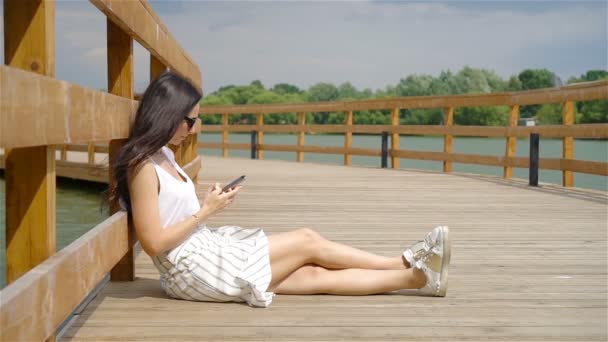귀여운 여자 가 공원에 앉아 있는 동안 휴대 전화로 문자 메시지를 읽고 있다. — 비디오