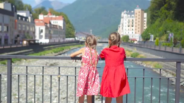 Vista posterior de las niñas en el terraplén de un río de montaña en una ciudad europea . — Vídeos de Stock