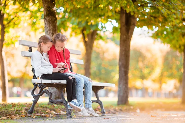 Pequenas meninas adoráveis com smartphone no outono ao ar livre . — Fotografia de Stock