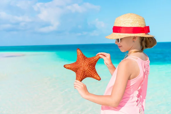 Menina adorável com estrela do mar na praia. Closeup estrela do mar nas mãos de uma menina — Fotografia de Stock