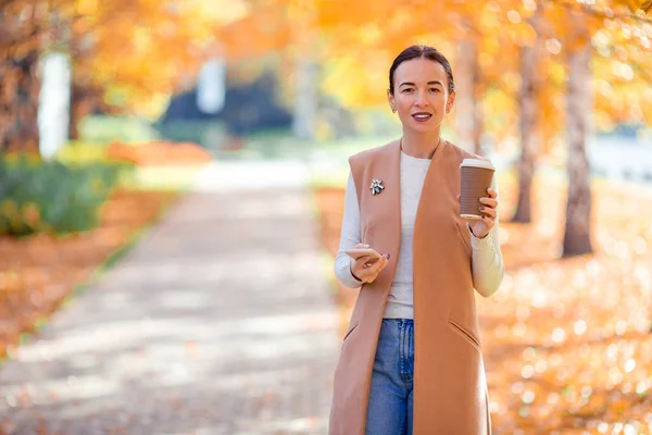 Herfst concept - mooie vrouw die koffie drinkt in het najaar park onder het gebladerte — Stockfoto