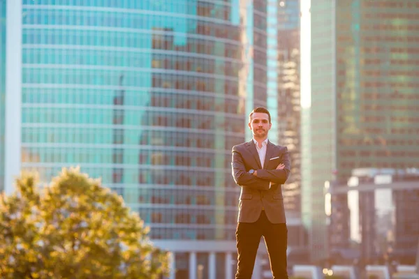 Empresario mirando el espacio de copia mientras está de pie contra el rascacielos de cristal — Foto de Stock