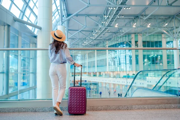 Mladá žena v klobouku se zavazadly na mezinárodním letišti. — Stock fotografie