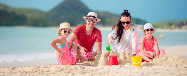 Familia haciendo castillo de arena en la playa tropical — Foto de Stock