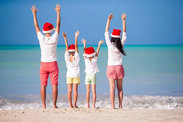 Glückliche Familie mit zwei Kindern in Santa Hat im Sommerurlaub — Stockfoto