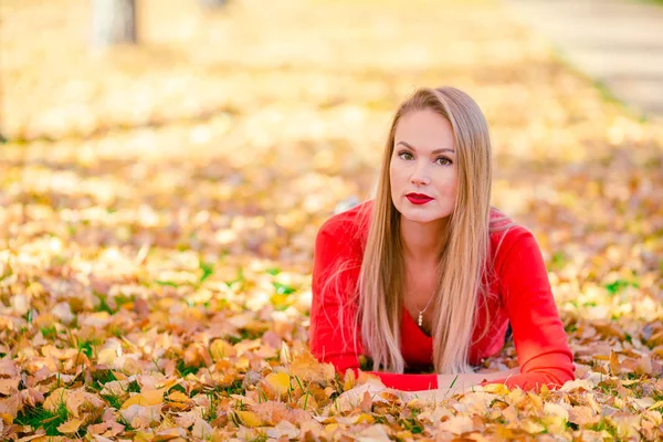 El concepto de otoño - la mujer hermosa que bebe café en el parque otoñal bajo el follaje otoñal —  Fotos de Stock