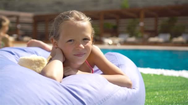 Hermosa niña divirtiéndose cerca de una piscina al aire libre — Vídeo de stock
